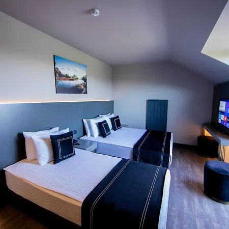 Menalo Hotel Premium Istanbul Airport Exterior photo The photo shows a modern hotel room featuring two beds with dark bedspreads, complemented by white linens and decorative pillows. The room has a stylish design, with a light color palette and minimalistic decor. There's a large flat-screen TV on one 